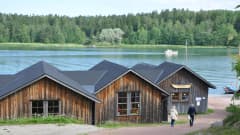 I förgrunden båtmuseet i Näsby med sina låga hus, i bakgrunden den blå Hålaxviken.