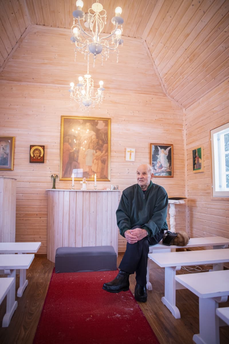 Teuvo Kostamo istuu vaaleasävyisen kirkon penkillä.