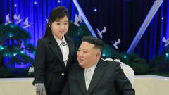 Nordkoreas ledare Kim Jong-Un sitter vid ett bord med dottern Kim Ju-Ae stående bredvid.