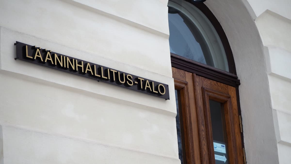 LÄÄNINHALLITUS-TALO nimikyltti talon seinässä puuoven vieressä.