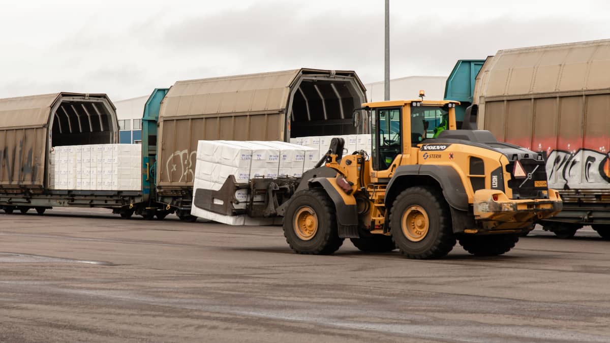 Traktori purkaa junasta UPM:n havusellu paaleja HaminaKotkan sataman D-terminaalin edustalla.