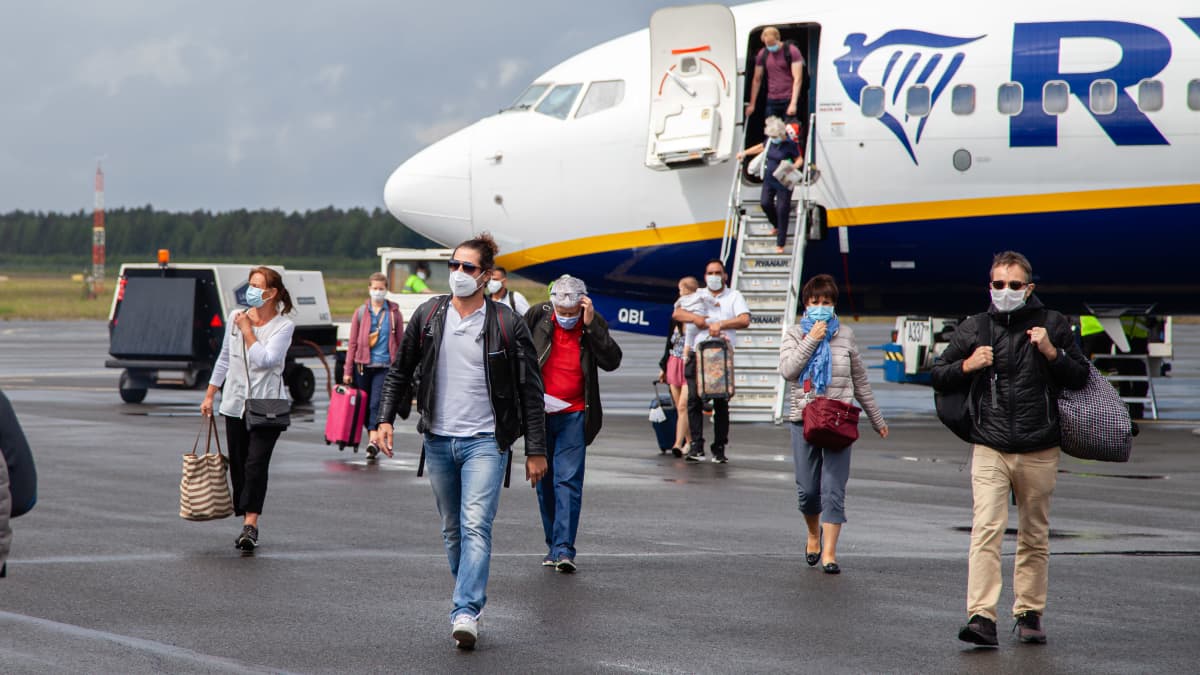 Italiasta tulleita ihmisiä kasvomaskeissa kävelee lentokoneesta Lappeenrannan lentoasemalla 1.7.2020.