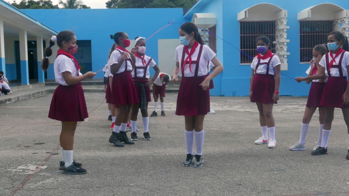 Havannan Pedro Domingo -peruskoulun oppilaat välitunnilla. Naruhyppelyssäkin on oltava maski naamalla, vaikka se helteisellä koulun pihalla tuntuu tukalalta.