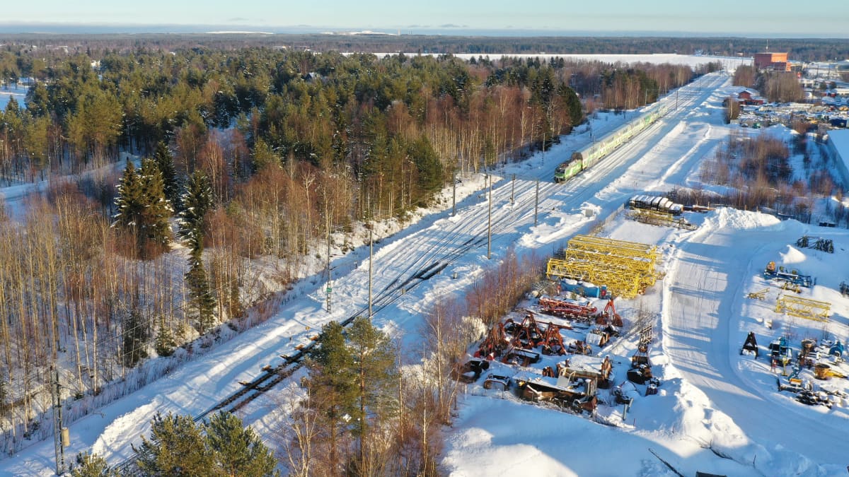 Juna saapuu Kemistä pohjoiseen päin. Maassa on lunta. Kaukana taustalla näkyy Isohaaran voimalaitos.