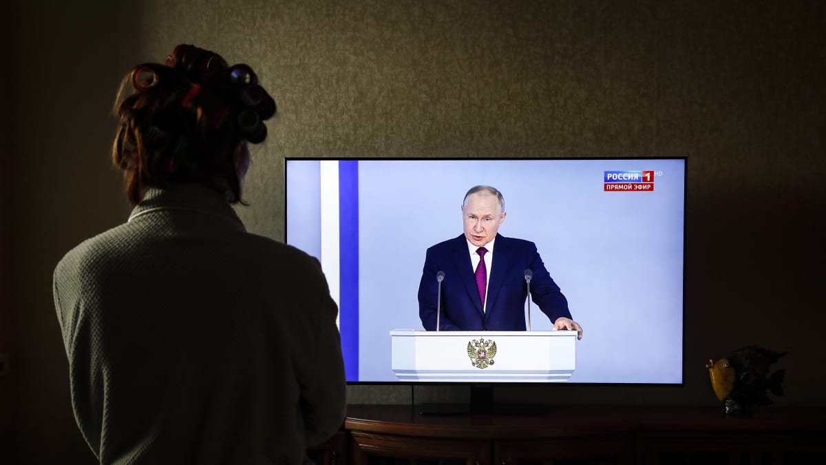 n kvinna tittar på den ryska presidenten Vladimir Putins tv-tal inför federala församlingen, i Moskva.