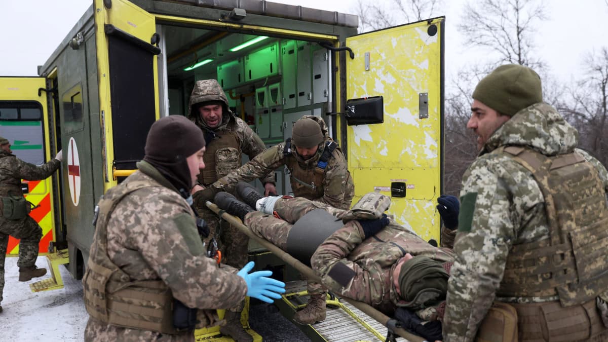 Armeijan lääkintähenkilöstö siirtää loukkaantunutta sotilasta ambulanssiin.