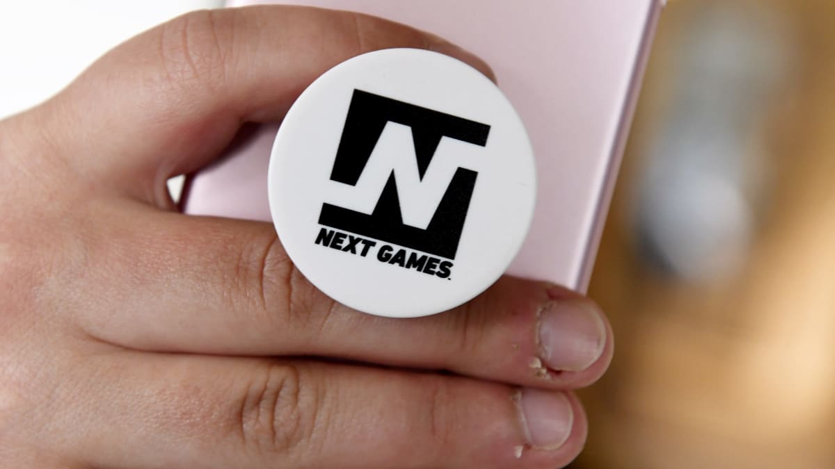 Next Games -logo puhelimen pidikkeessä.