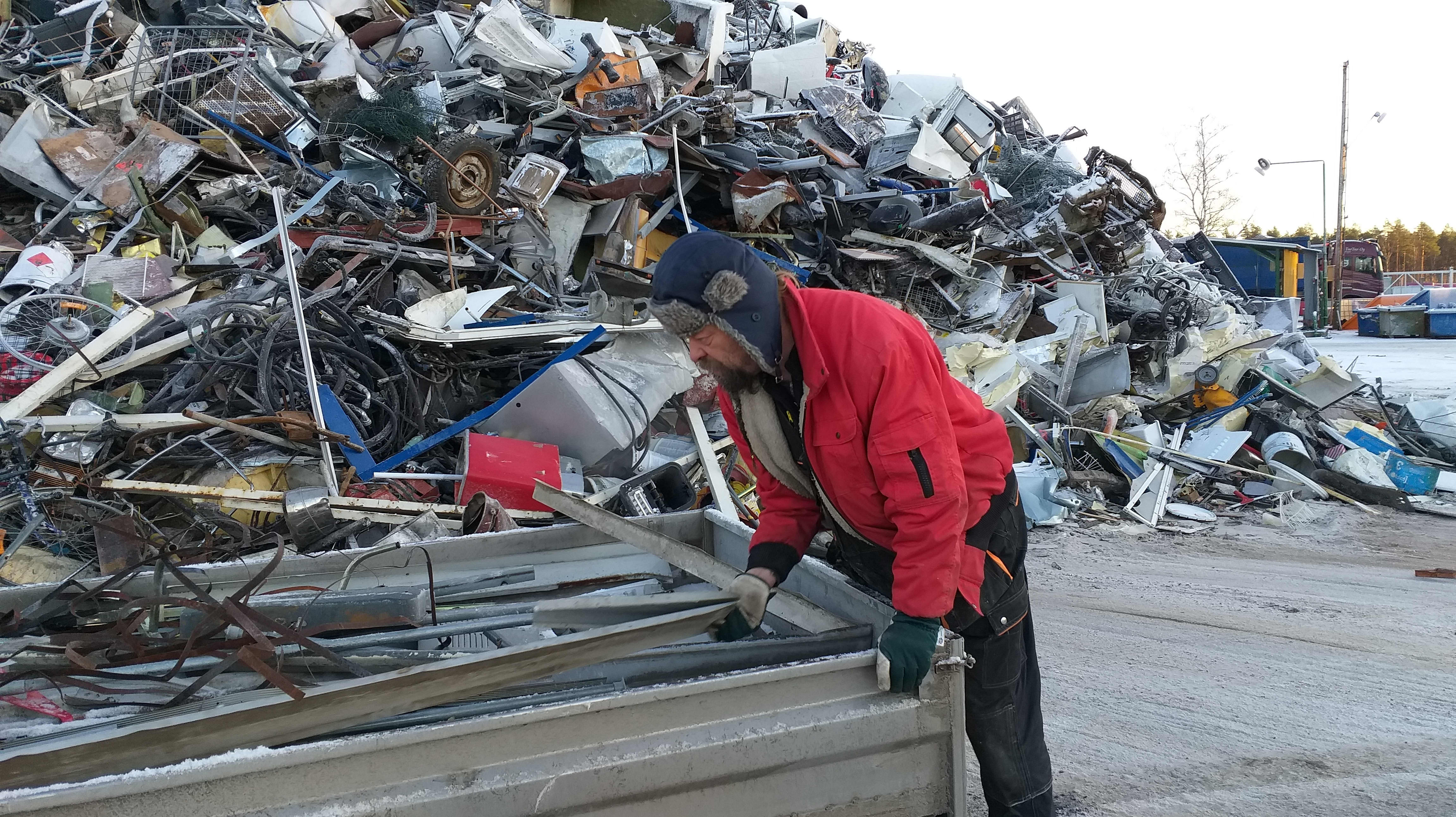 Mies tuo metalliromua peräkärryssä romuttamolle.