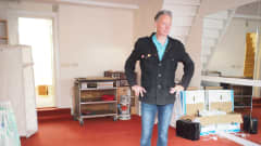 Mies seisoo huoneessa missä on punainen kokolattia matto.