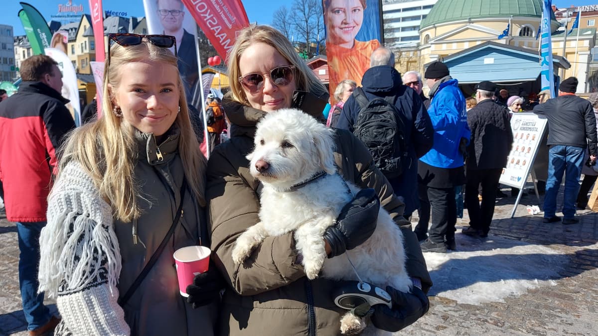 Olivia Honkonen ja koira sylissä Anne Harjuvaara Turun Kauppatorilla.