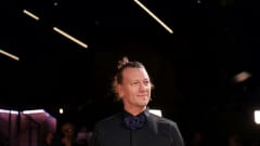 Duudsoneiden Jukka Hildén puolikuvassa mustassa kauluspaidassa mustaa taustaa vasten ponnari päässään.