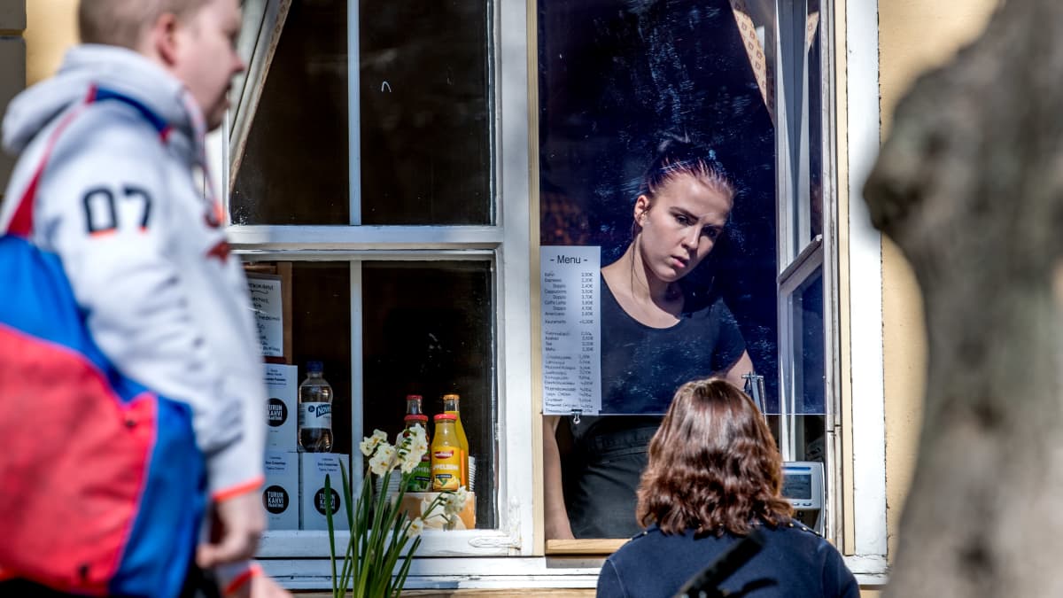 En kvinna säljer kaffe i ett fönster.