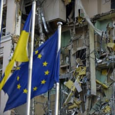 Ukrainan ja Eu:n liput tuhoutuneen hotellirakennuksen edessä Kiovassa.