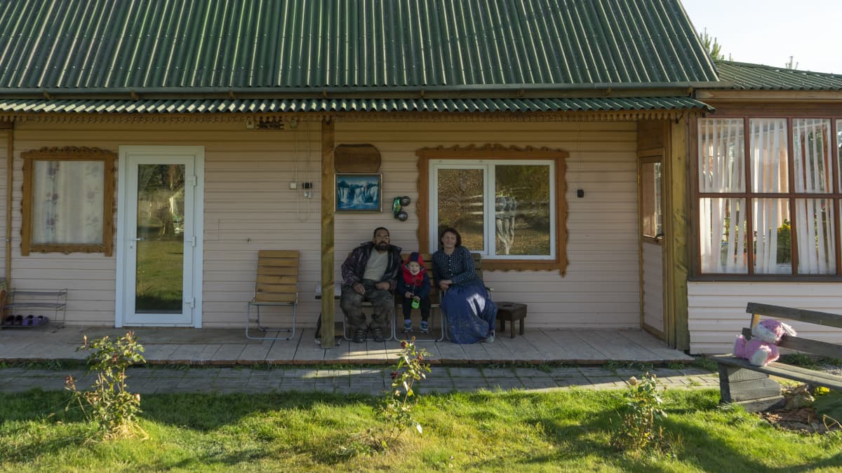 Perhe istuu talon kuistilla.