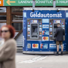 Mies nostaa käteistä automaatilta, jossa lukee saksaksi Geldautomat.