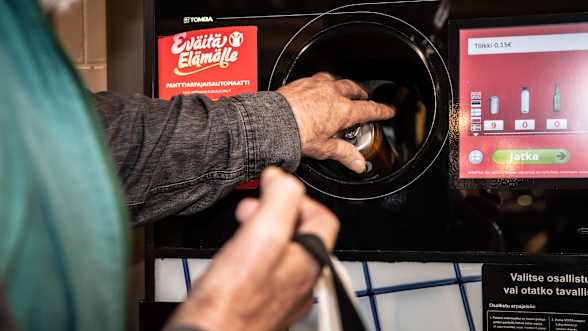 A person inserts a bottle into a recycling machine.