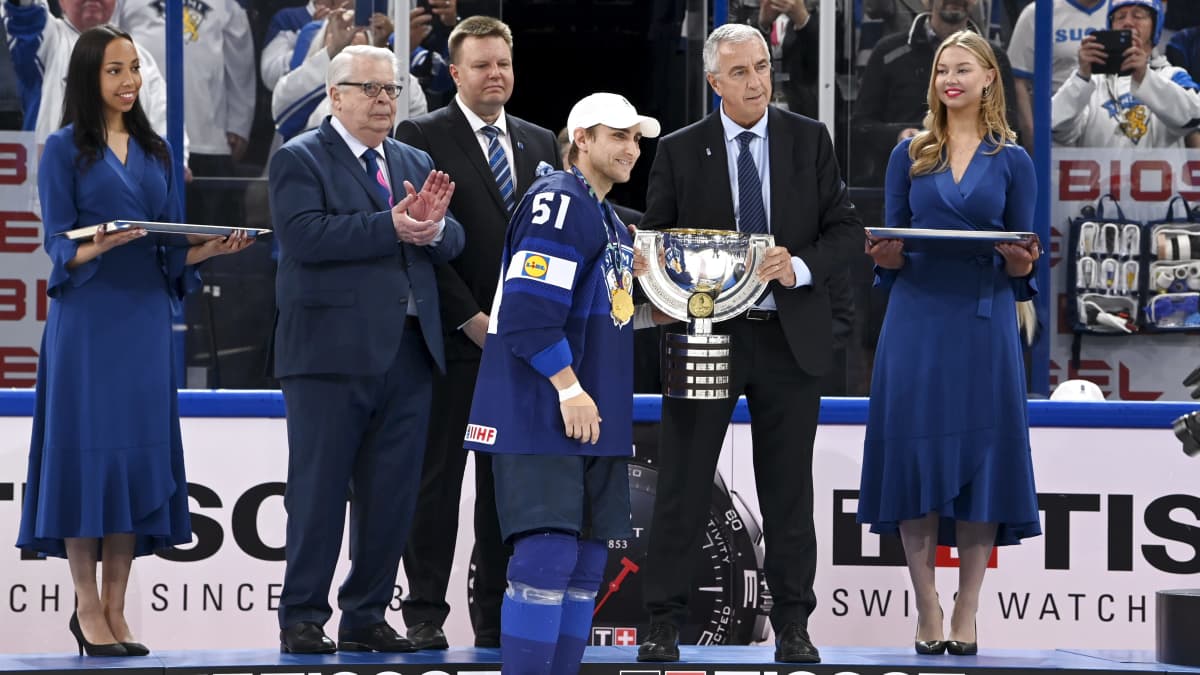 Valtteri Filppula hakee palkintopokaalia jääkiekon MM-kisojen finaalin jälkeen. Taustalla muun muassa Kalervo Kummola sekä kaksi mitalienjaossa avustanutta naista.