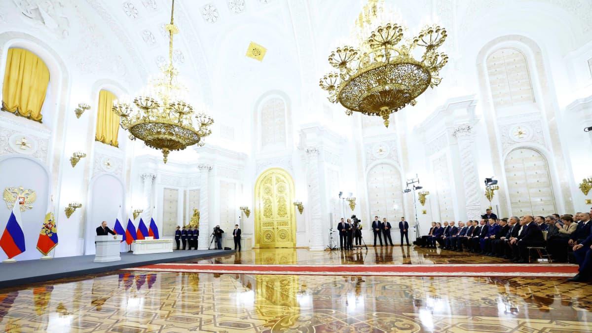 Vladimir Putin puhuu suuressa salissa Kremlissä. Yleisö kuuntelee etäisyyden päässä.