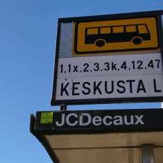 Lähikuvassa bussipysäkin kyltti ja linjanumerot