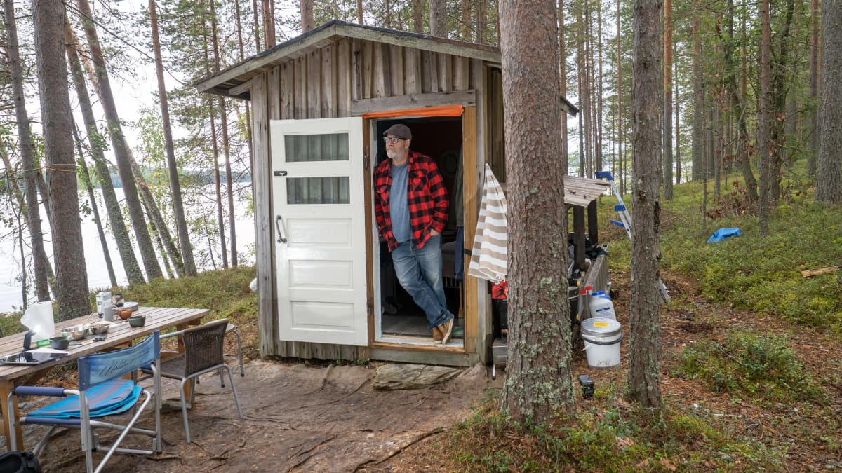 Mies seisoo mökin oviaukossa
