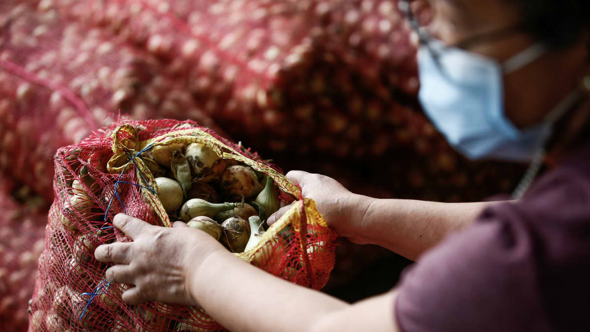 Filippiiniläinen nainen nostelee sipulisäkkejä.