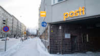A building on a snow-covered city street. The building's entrance has two signs that say "Posti" on them.