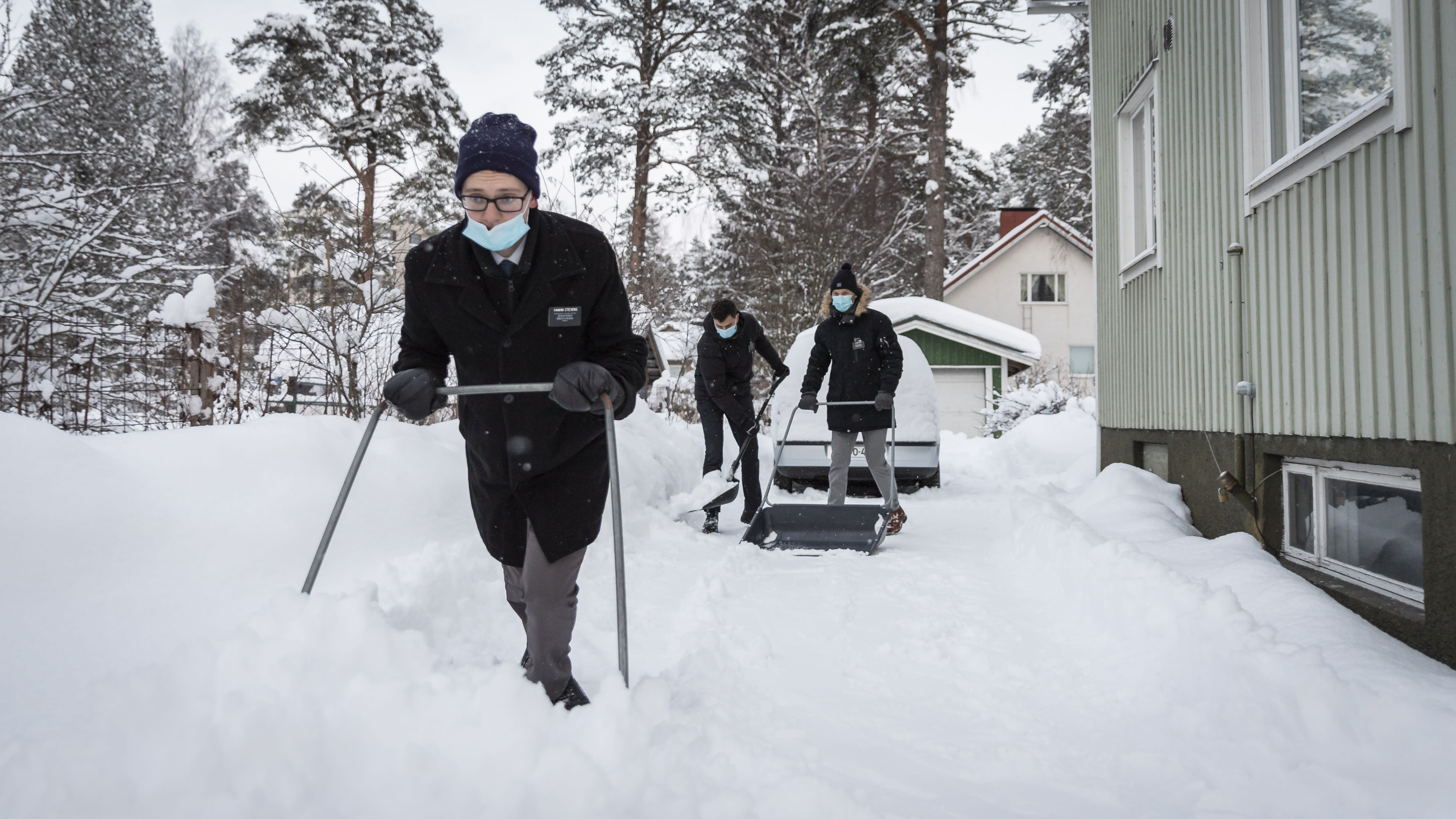 Harlan Stevens ja kaksi muuta kirkon jäsentä kolaamassa lunta omakotitalon pihatiellä. 