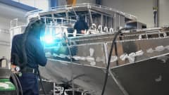 Två personer svetsar på två olika aluminiumbåtar.