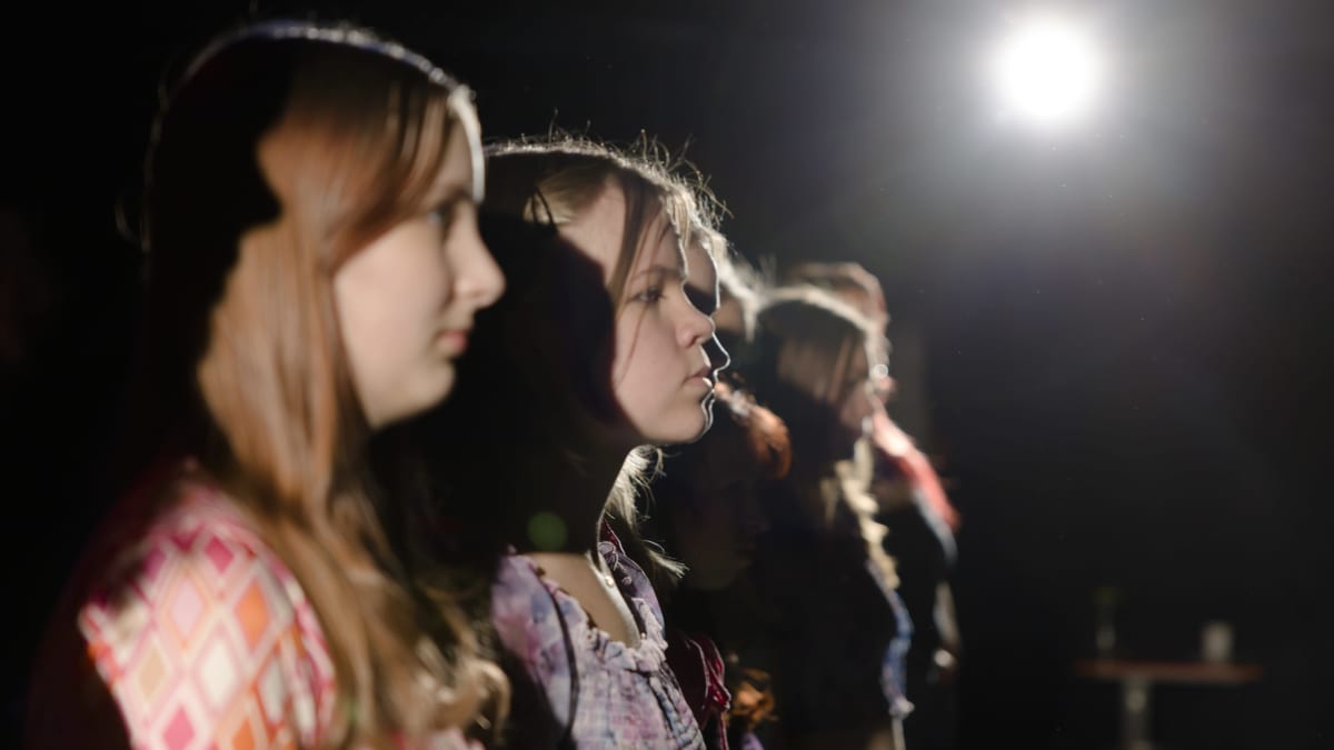Nuoria naisia seisomassa vierekkäin teatterin lavalla.