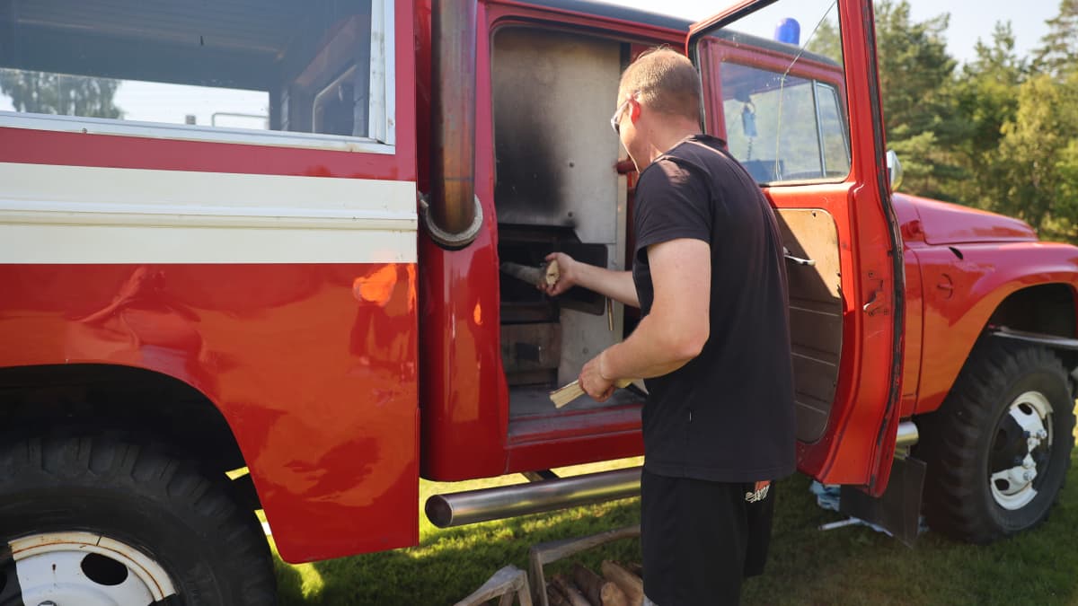 Antti Nisula laittaa puita saunan pesään, joka on tehty vanhaan paloautoon.