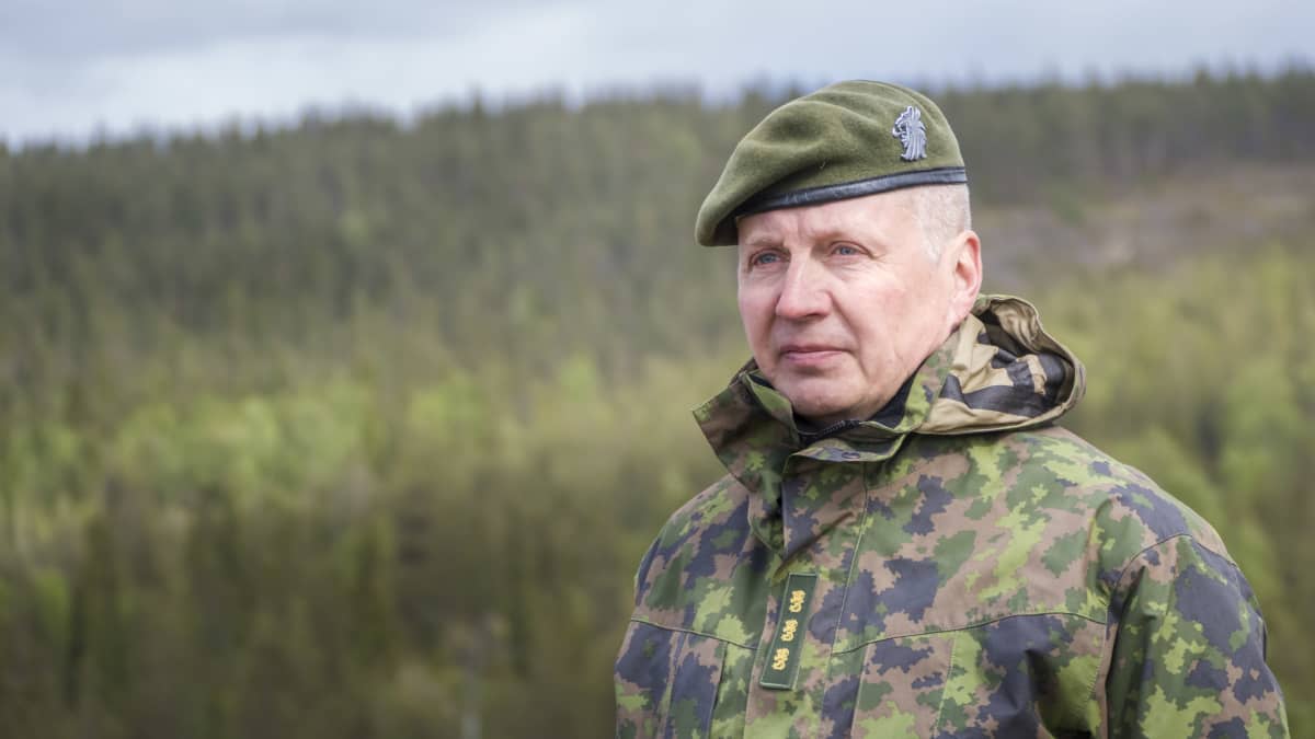 Maavoimien komentaja Petri Hulkko rintakuvassa maastopuvussa metsämaisemaa vasten.