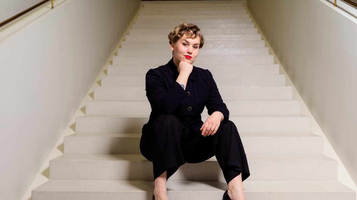 Eve Kulmala istuu kaupungintalon aulan portaikossa.