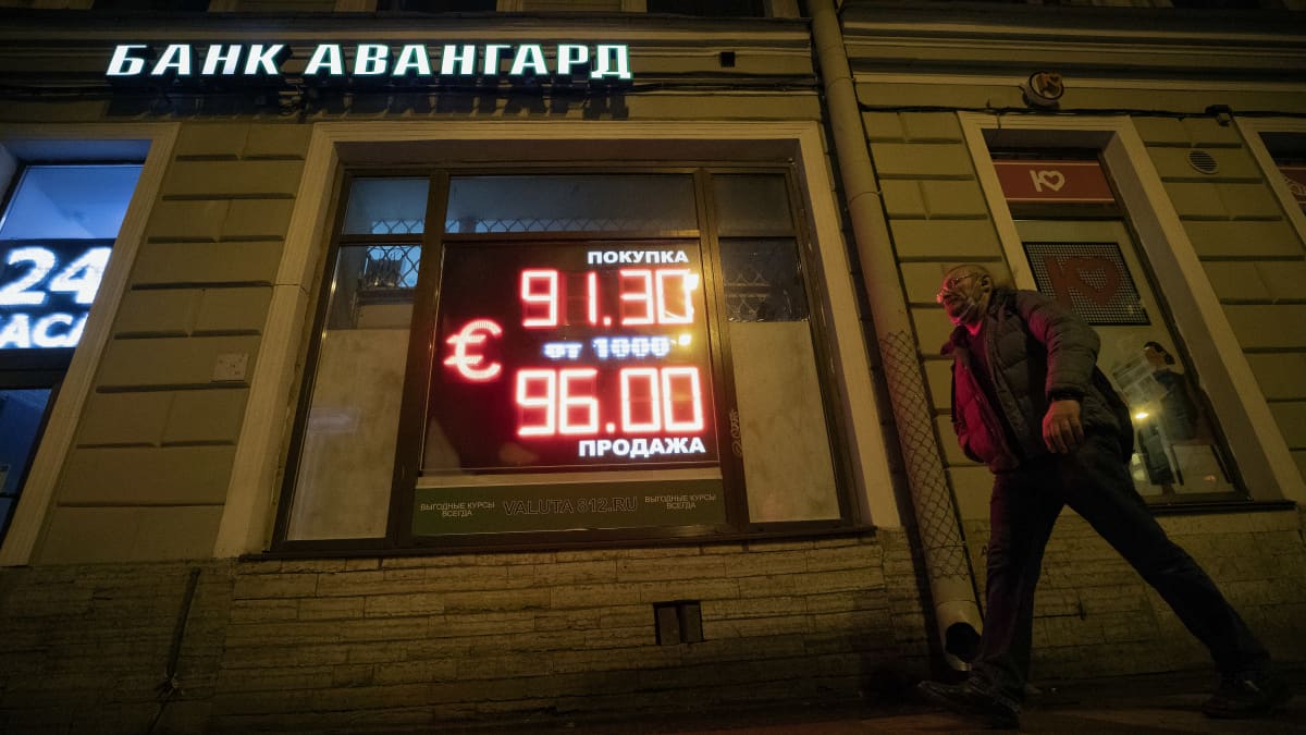 Ihminen kävelee valotaulun ohi, jossa johtaa punaisella numeroita ja euron merkki.