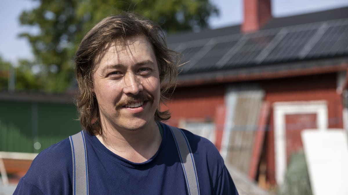 Hymyilevä mies, taustalle vaja jonka katolla on aurinkopaneelit.