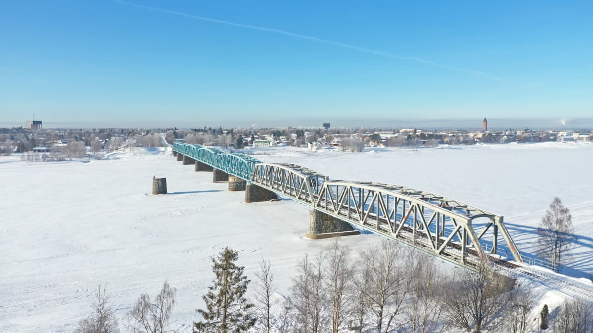 Haaparannan ja Tornio välinen rautatiesilta kulkee Tornionjoen yli. Kuva on otettu talvella ja joki on jäässä. Taistalla häämöttää Haaparanta.
