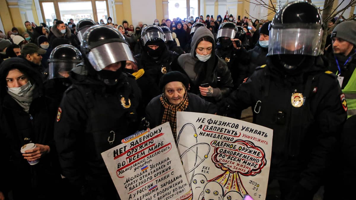 Mellakkapoliisit piirittävät naista mielenosoituksessa.