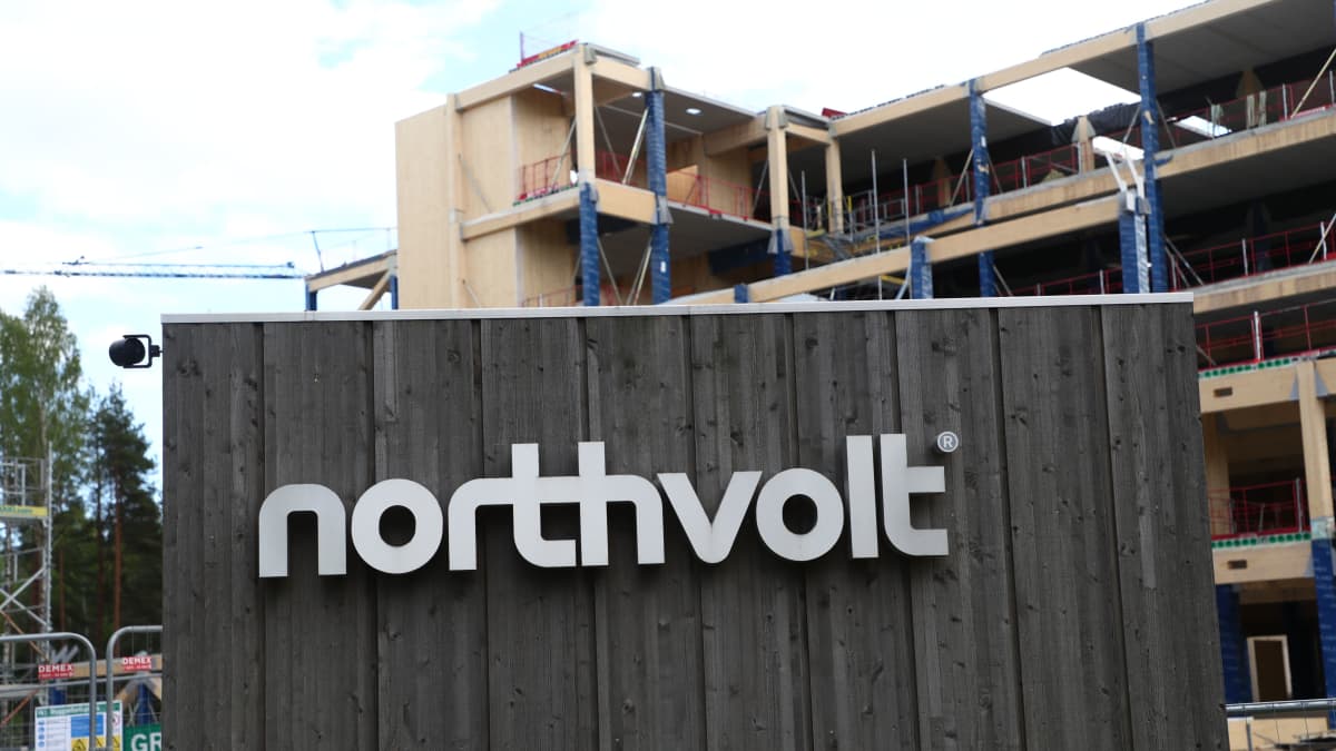 Etualalla Nortvoltin logo puutaustalla, taustalla näkyy viisikerroksisen tuotantorakennuksen työmaa.