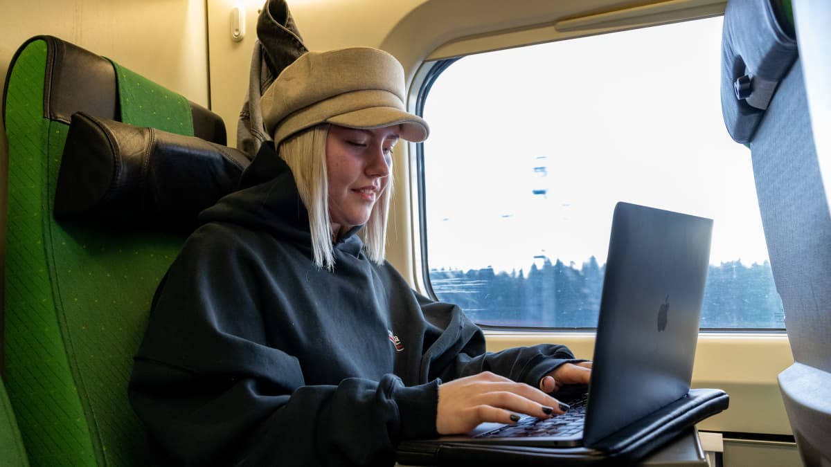 Vaasalainen Emilia Pörsti junan kyydissä tietokoneen ääressä.