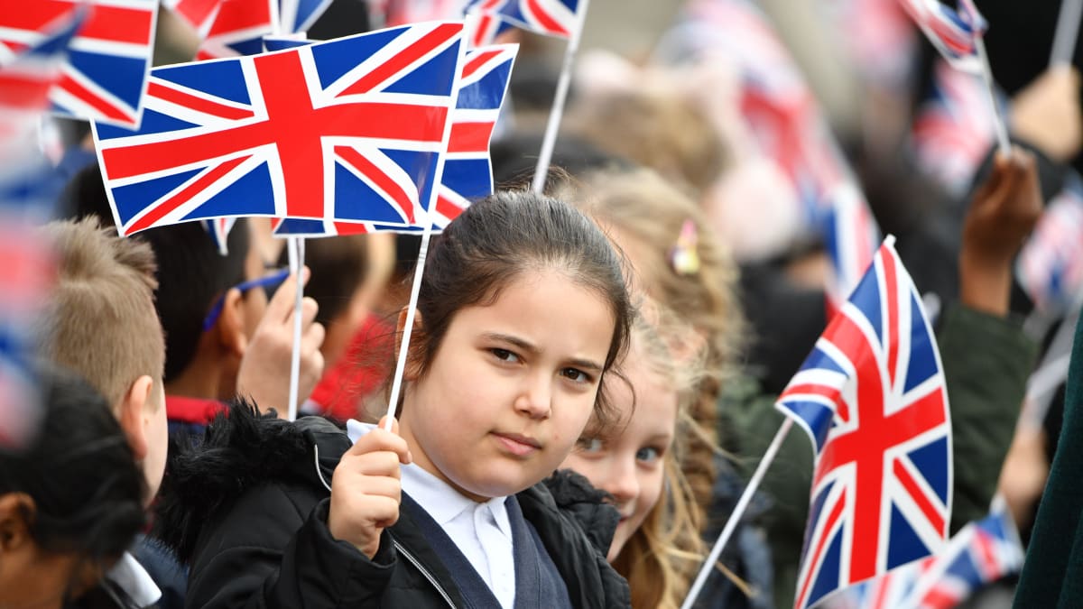 Koululaiset heiluttavat pieniä Britannian lippuja.