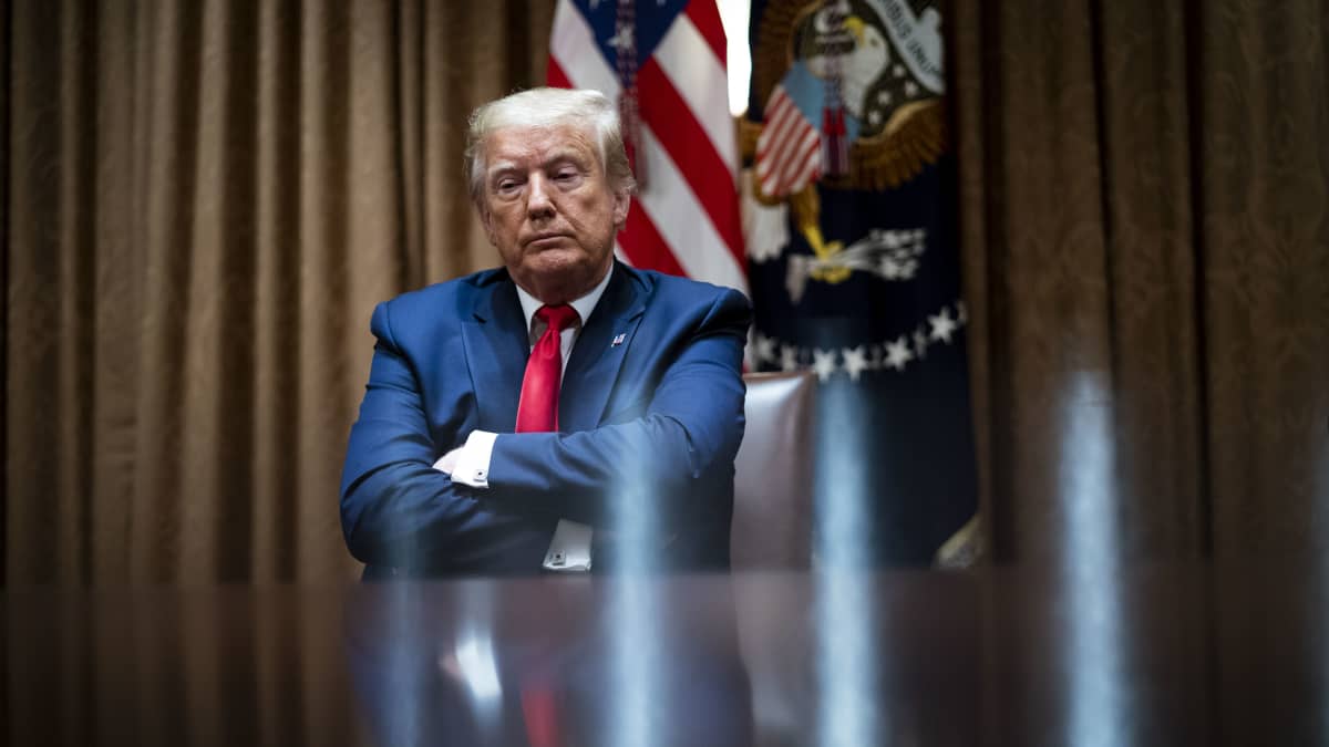 Trump istuu kädet puuskassa Valkoisessa talossa.