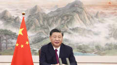 Xi puhuu, taustalla vuoristomaisema maalaus ja Kiinan lippu. 