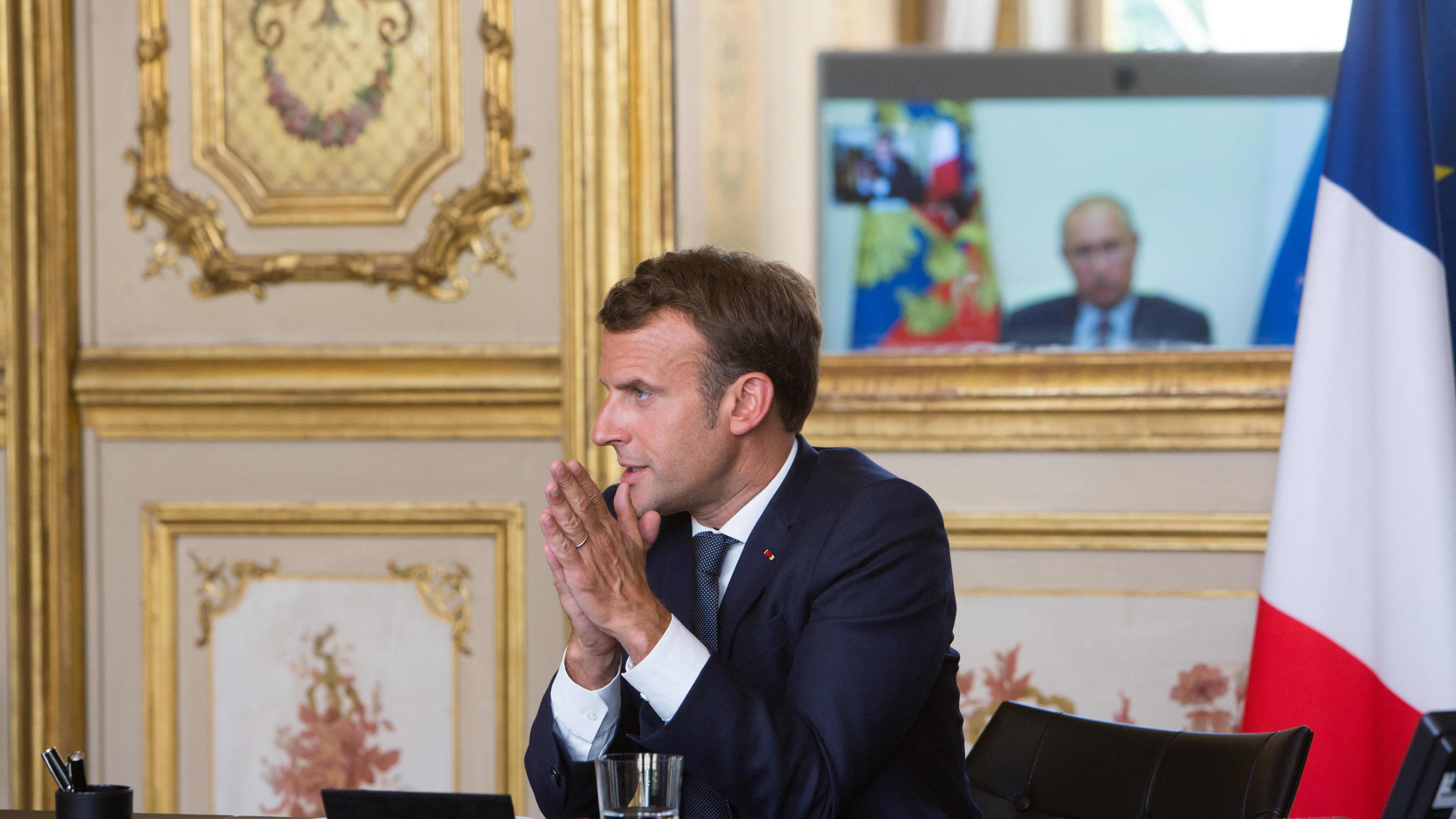 Presidentit Macron ja Putin keskustelevat videoyhteyden välityksellä. Putin istuu työpöytänsä äärelle, taustalla Putinin kasvot erottuvat televiosruudulta. 