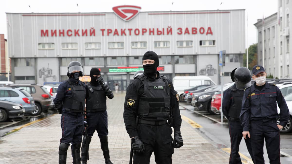 Joukko miliisin OMON-erikoisjoukkojen jäseniä seisoo Minskin traktoritehtaan edustalla tummissa univormuissa ja mellakkavarusteissa.