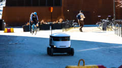 Valkoinen, laatikonmallinen kuljetusrobotti lähtee kuljettamaan ruokaostoksia Otaniemen Alepalta tilaajalle.