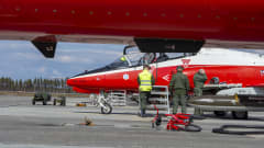 Kolme miestä tekemässä lentoonlähtötarkistusta punavalkoiseksi maalatun hävittähän luona.