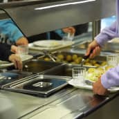 Hirvelän koulun oppilaat ottamassa kouluruokaa lautaselle ruokalinjastolla.