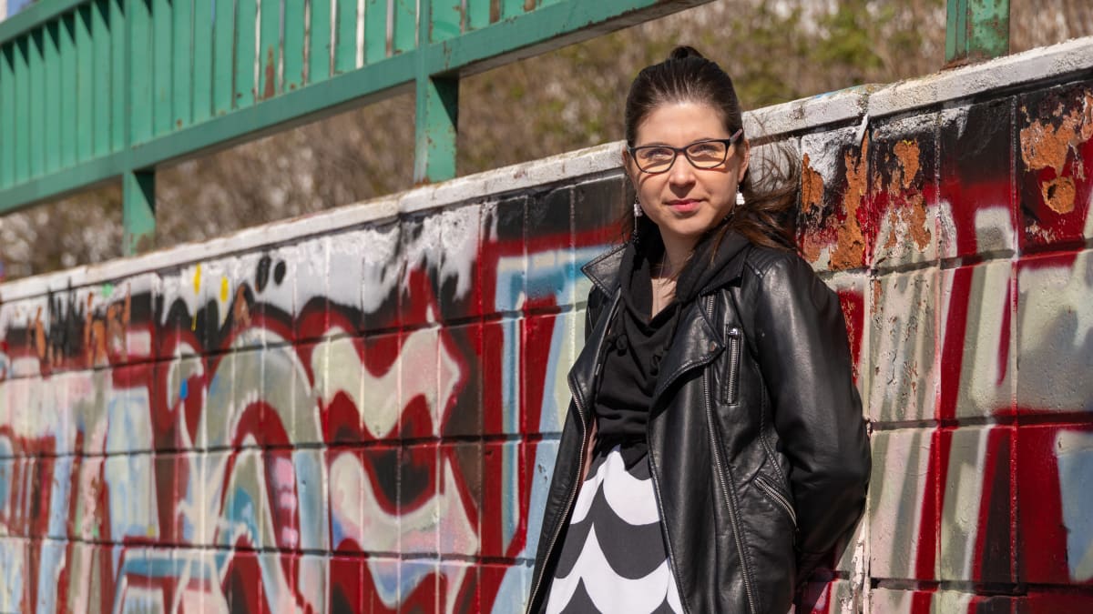 Rovaniemen kaupungin nuorisopalvelujen nuorisotoiminnan koordinaattori Henrietta Kangas nojaa graffitiseinää vasten.