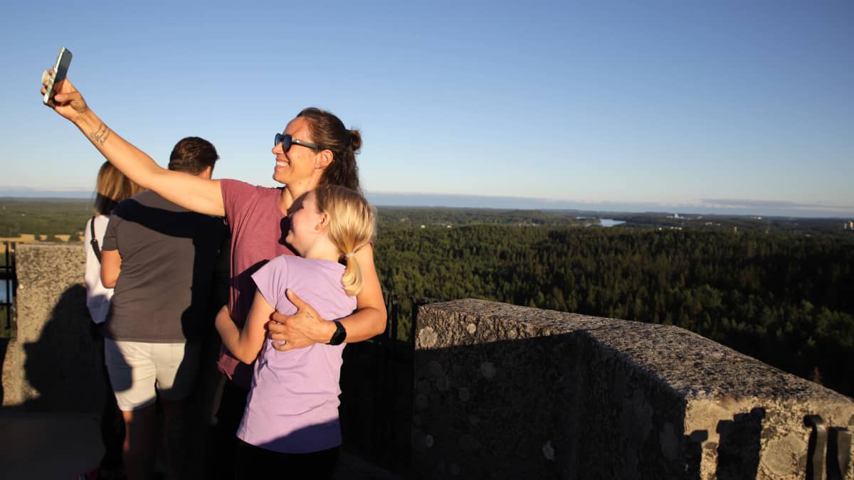Annika ja Venla Halkosaari ottavat selfietä Aulangon näkötornin huipulla elokuisessa ilta-auringossa taustalla tornista avautuva metsämaisema.