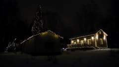 Mikkelin Emolassa sijaitseva, jouluvaloin koristeltu talo ja korkea kuusi.