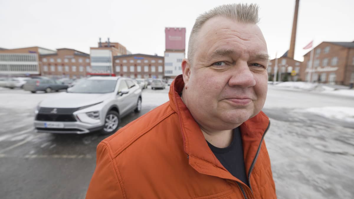 Mies parkkipaikalla autonsa edessä